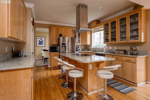 kitchen featuring a kitchen breakfast bar, island exhaust hood, a center island, light stone counters, and black appliances