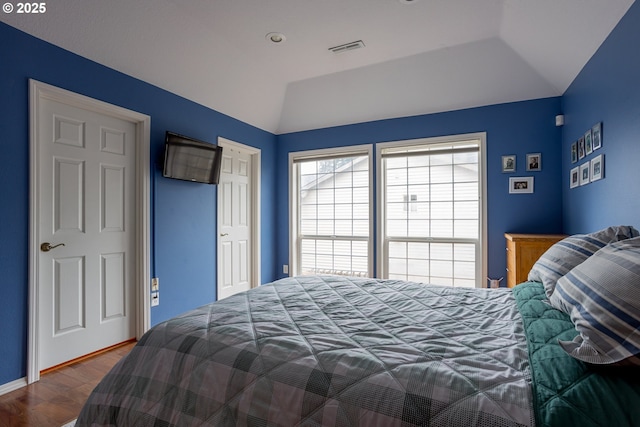 bedroom with vaulted ceiling, dark wood-type flooring, and a closet