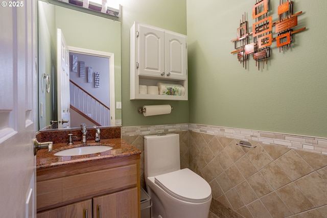 bathroom featuring vanity, toilet, and tile walls