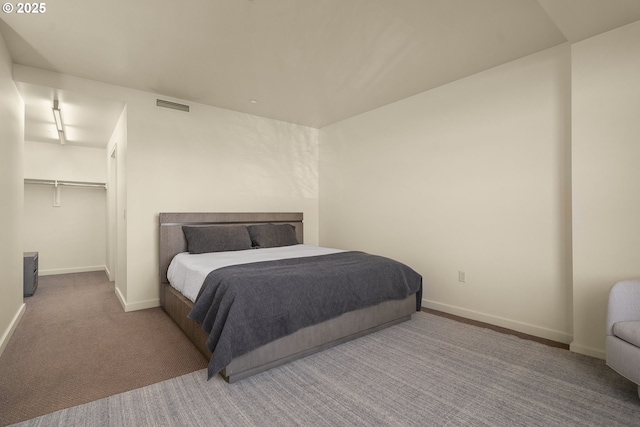 bedroom with a walk in closet and light carpet