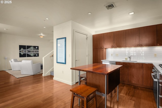 kitchen featuring tasteful backsplash, sink, hardwood / wood-style floors, and stainless steel appliances