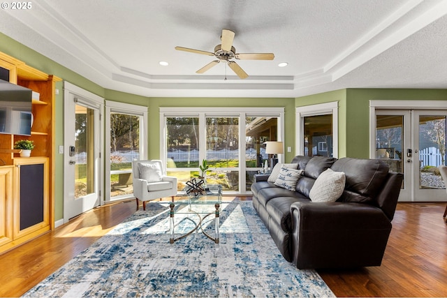 sunroom / solarium with a tray ceiling, a ceiling fan, and french doors