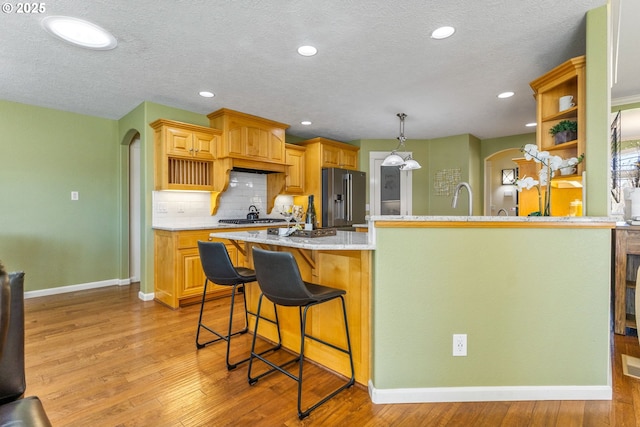 kitchen featuring light wood finished floors, high quality fridge, and arched walkways