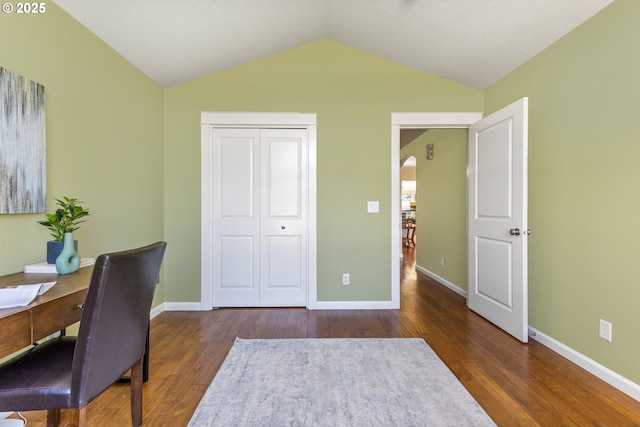 office space featuring arched walkways, vaulted ceiling, wood finished floors, and baseboards