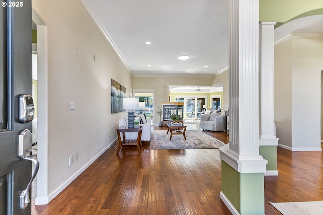 foyer with ornate columns, crown molding, baseboards, and hardwood / wood-style floors