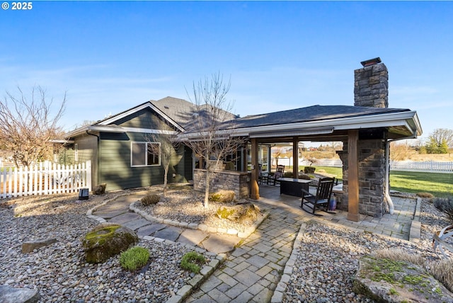 rear view of house with a patio area, a chimney, fence, and roof with shingles