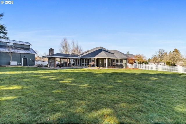 rear view of property with a standing seam roof, a fenced backyard, metal roof, and a lawn