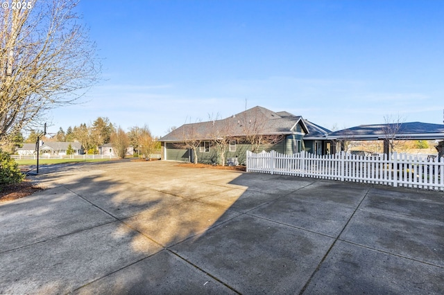 view of front facade featuring concrete driveway and fence