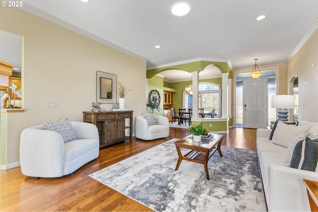 living area featuring arched walkways, wood finished floors, and recessed lighting