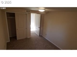 unfurnished bedroom with dark carpet and a closet