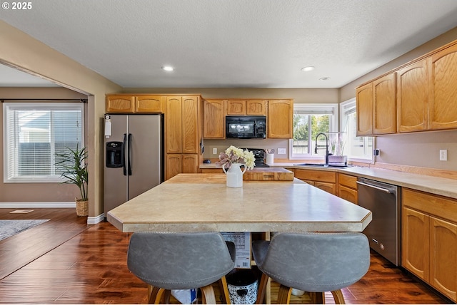kitchen with a textured ceiling, dark wood-style flooring, light countertops, a sink, and stainless steel appliances