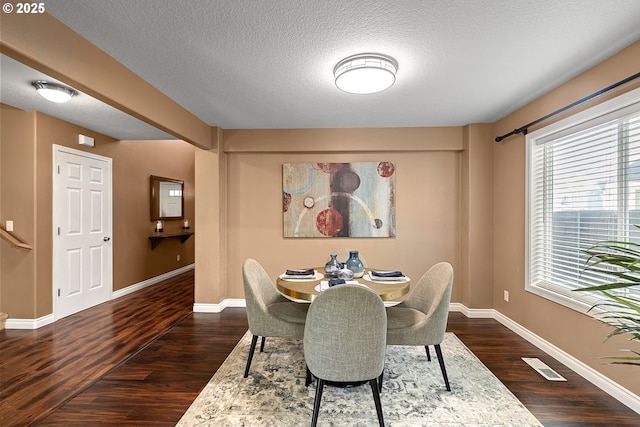 dining area with a textured ceiling, baseboards, dark wood-style floors, and visible vents