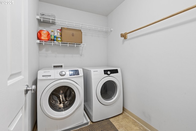 clothes washing area featuring laundry area, separate washer and dryer, light tile patterned floors, and baseboards