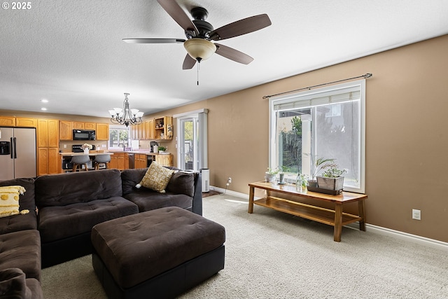 living area with baseboards, recessed lighting, light carpet, and ceiling fan with notable chandelier