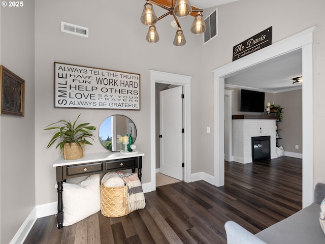 entrance foyer with a glass covered fireplace, visible vents, baseboards, and wood finished floors