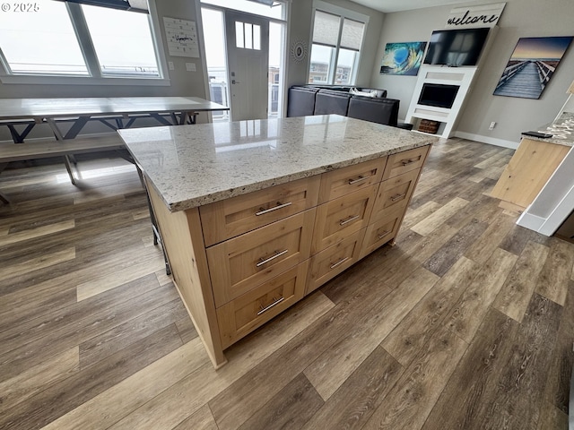 6604 NE Logan Rd, Lincoln City, OR 97367 - kitchen with dark wood-style floors, a fireplace, light stone countertops, a kitchen island, and open floor plan