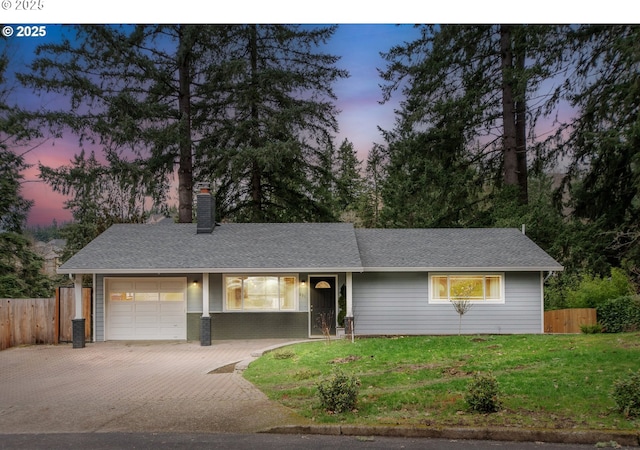 single story home with a garage, decorative driveway, a yard, and fence