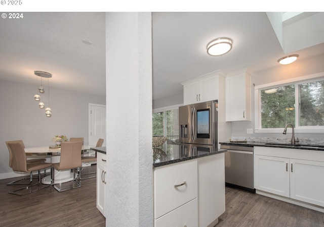 kitchen featuring appliances with stainless steel finishes, sink, white cabinetry, dark stone counters, and dark hardwood / wood-style floors