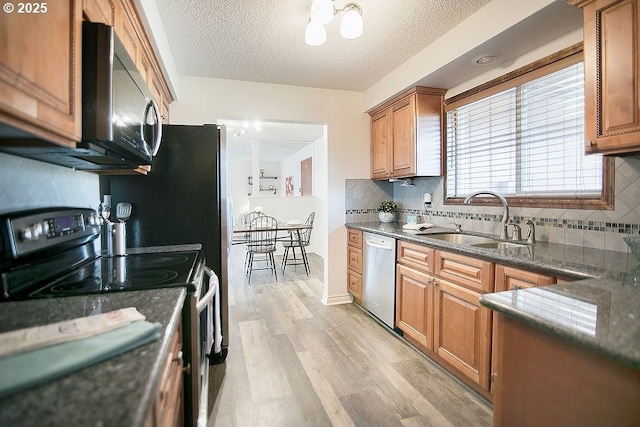 kitchen featuring stainless steel dishwasher, brown cabinetry, a sink, light wood-type flooring, and range with electric cooktop