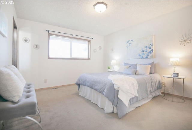 carpeted bedroom featuring a textured ceiling, visible vents, and baseboards