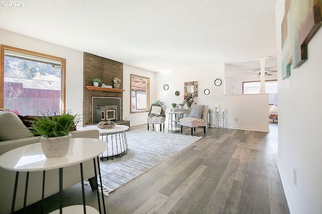 living room featuring a ceiling fan, baseboards, a textured ceiling, and wood finished floors