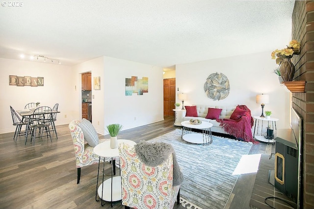 living area with a fireplace, a textured ceiling, baseboards, and wood finished floors