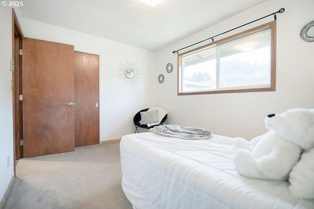 bedroom featuring a textured ceiling and light colored carpet