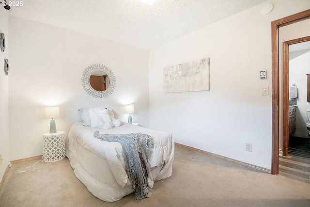 bedroom with light colored carpet, a textured ceiling, and baseboards