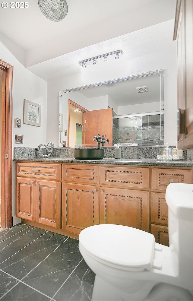 bathroom featuring double vanity, a stall shower, toilet, marble finish floor, and a sink