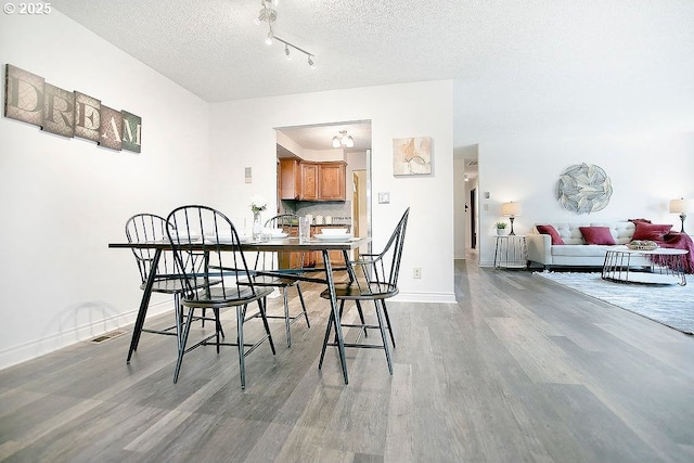 dining room featuring light wood finished floors, visible vents, baseboards, and a textured ceiling