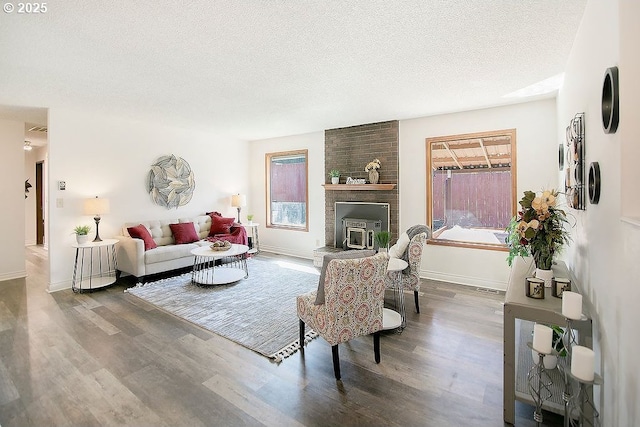 living area with a textured ceiling, baseboards, and wood finished floors