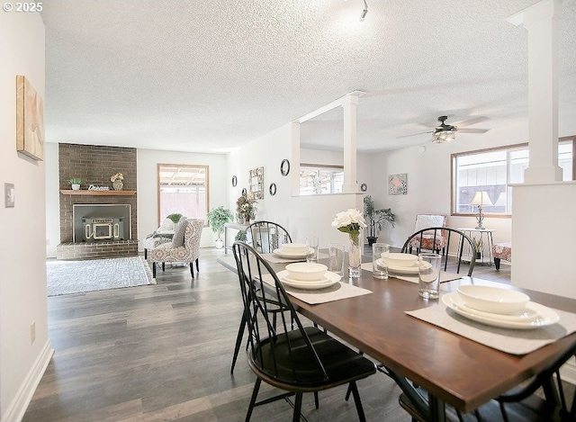 dining room featuring wood finished floors, decorative columns, a wealth of natural light, and a ceiling fan