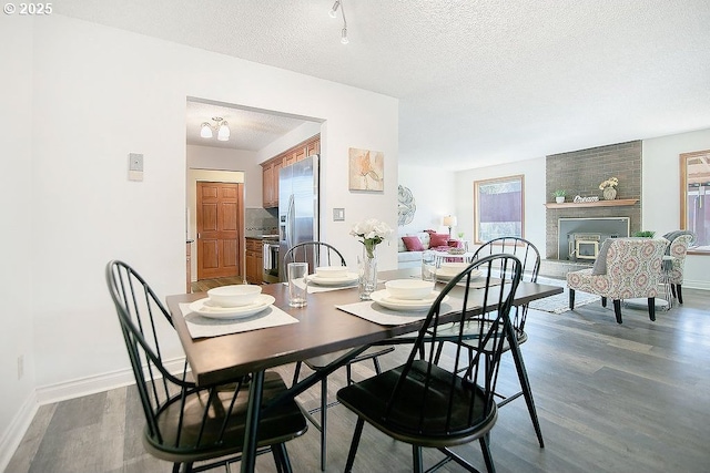 dining area featuring a textured ceiling, baseboards, and wood finished floors