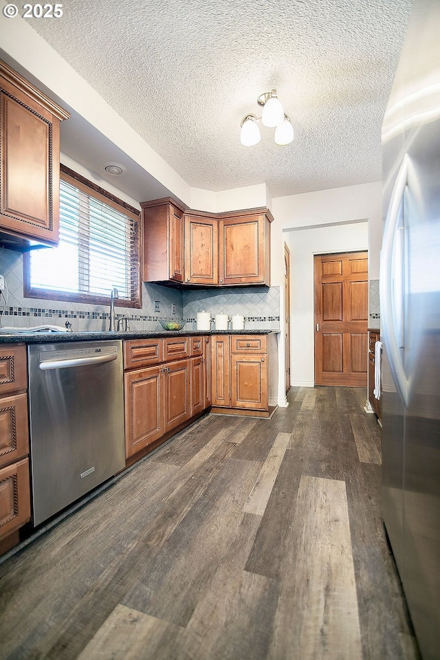 kitchen featuring dark countertops, dark wood finished floors, dishwasher, and refrigerator