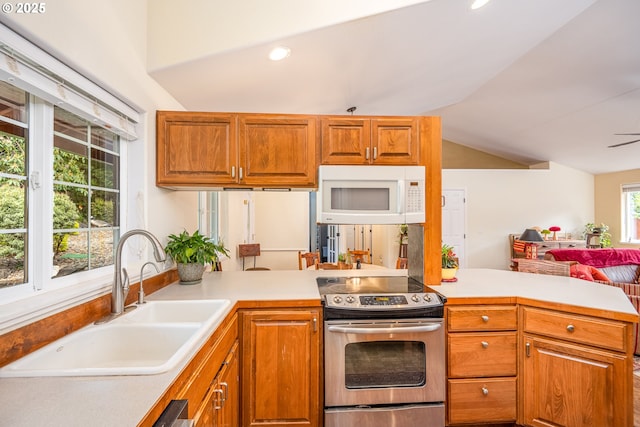 kitchen with stainless steel range with electric stovetop, white microwave, a sink, lofted ceiling, and light countertops