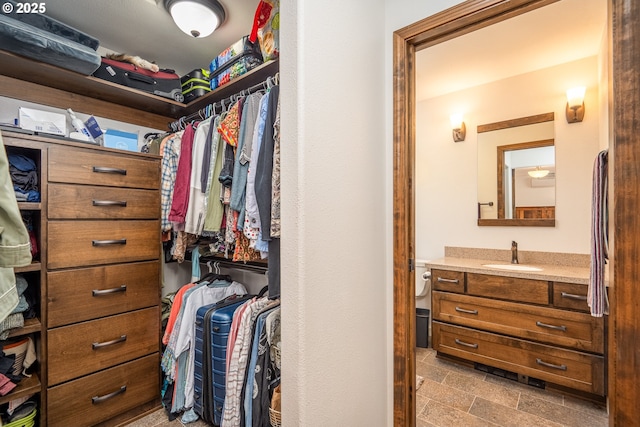 spacious closet with a sink and stone finish floors