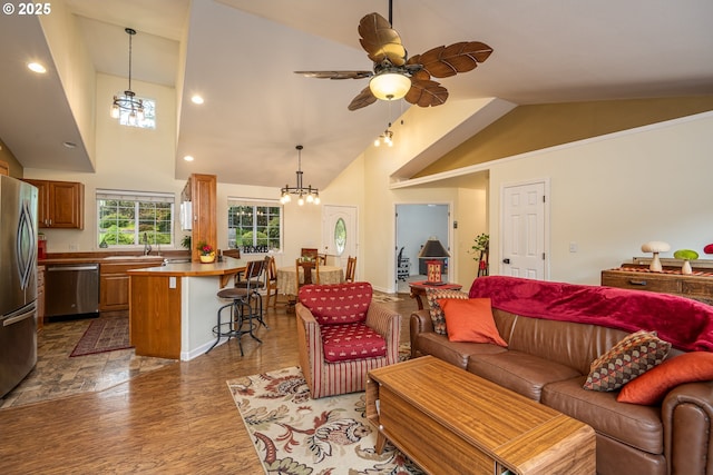 living room with wood finished floors, a ceiling fan, high vaulted ceiling, and a chandelier
