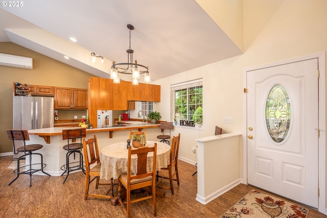 dining space featuring lofted ceiling, wood finished floors, a wall mounted air conditioner, and baseboards
