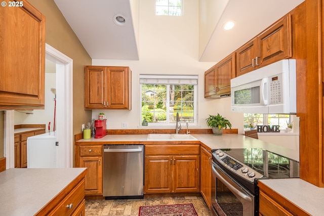 kitchen with appliances with stainless steel finishes, a sink, brown cabinetry, recessed lighting, and lofted ceiling
