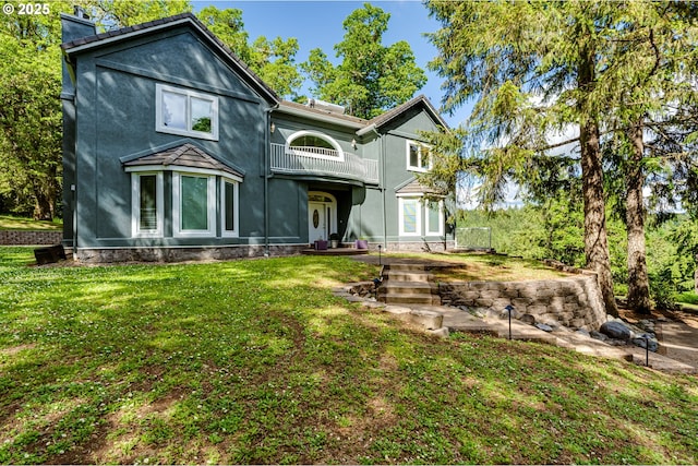 27161 Briggs Hill Rd, Eugene, OR 97405 - back of house featuring a balcony, a lawn, a chimney, and stucco siding