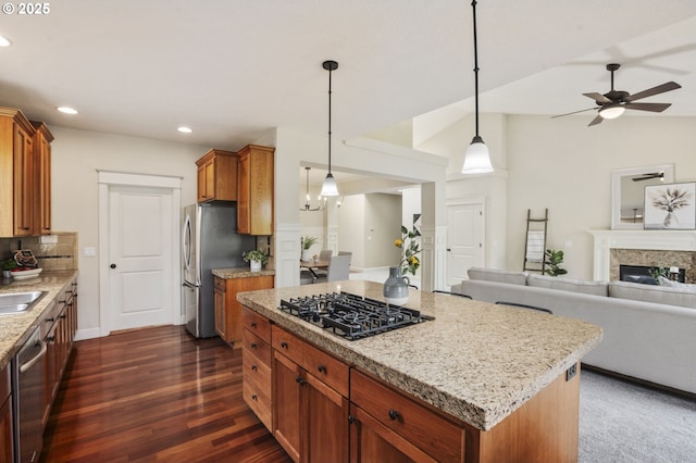 kitchen featuring open floor plan, dark wood-style flooring, light stone countertops, stainless steel appliances, and a fireplace