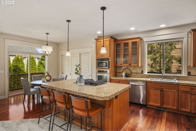 kitchen with appliances with stainless steel finishes, backsplash, a kitchen island, and a sink