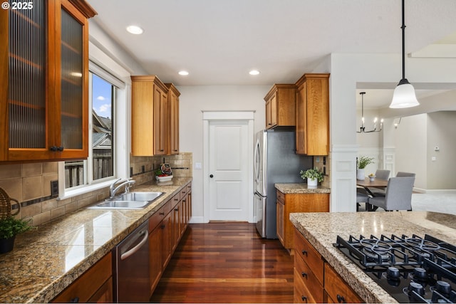 kitchen with brown cabinets, tile counters, stainless steel appliances, and a sink