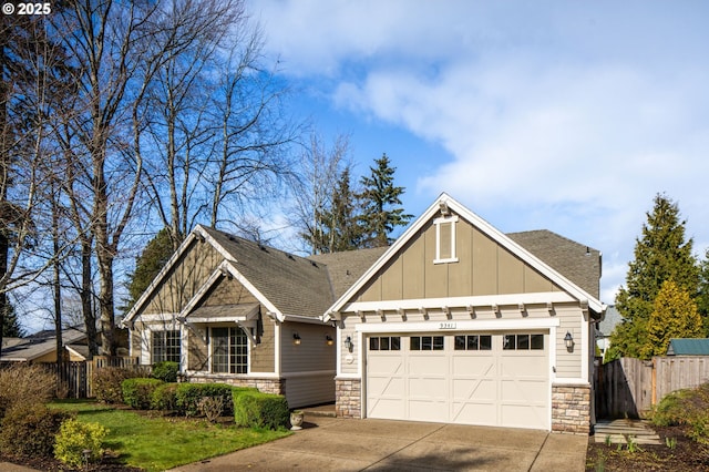 craftsman-style house featuring a garage, fence, driveway, stone siding, and board and batten siding