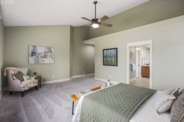 bedroom with baseboards, light colored carpet, ensuite bath, ceiling fan, and high vaulted ceiling