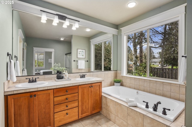 full bath featuring double vanity, a garden tub, a sink, and tile patterned floors