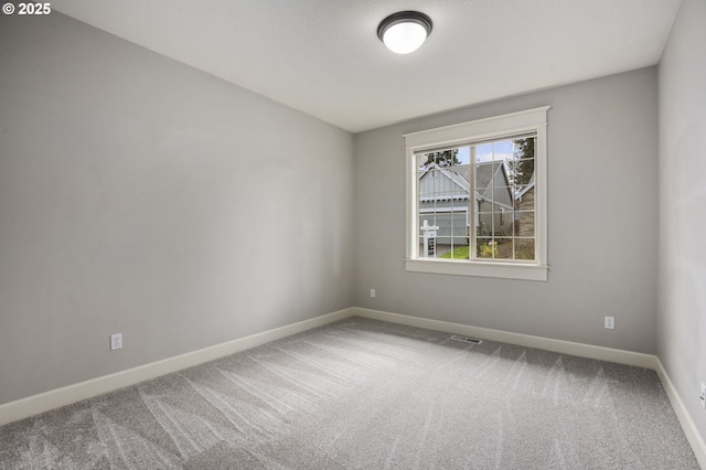 unfurnished room with visible vents, baseboards, and carpet flooring