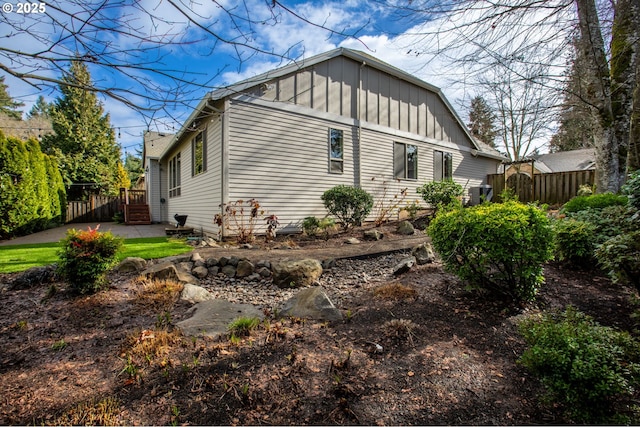 view of property exterior with a patio area, cooling unit, fence, and board and batten siding