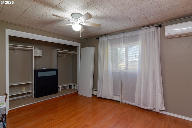 78613 Powerline Rd, Hermiston, OR 97838 - unfurnished bedroom with a wall mounted AC, wood finished floors, baseboard heating, and ceiling fan