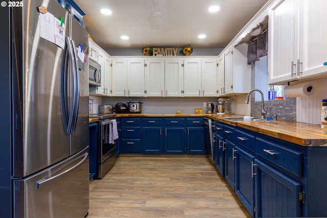 78613 Powerline Rd, Hermiston, OR 97838 - kitchen with appliances with stainless steel finishes, blue cabinets, butcher block countertops, white cabinets, and light wood-style floors